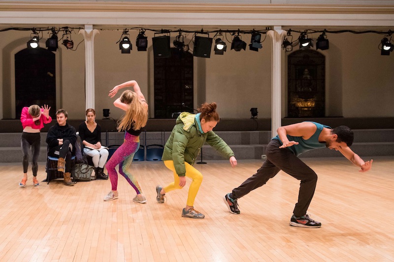 Sterling Hyltin shields her eyes as Sara Mearns, Jodie Melnick and Rashaun Mitchen dance on a diagonal wearing haphazard colorful clothes
